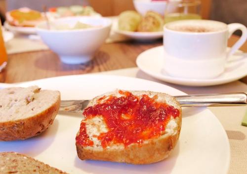 a piece of bread with jam on a plate with a cup of coffee at Garni Lanzinger in Selva di Val Gardena