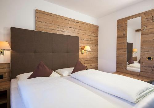 a bedroom with a large white bed and a mirror at Garni Lanzinger in Selva di Val Gardena