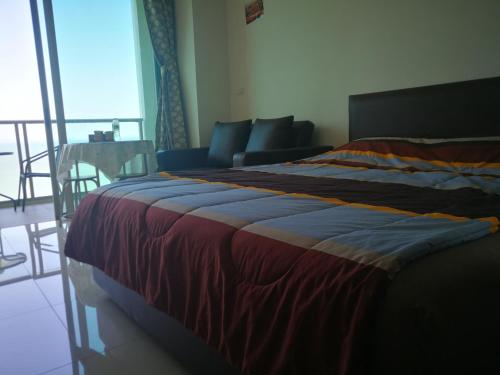 a bedroom with a bed and a couch and a table at The Riviera Wongamat Hong Apartment in Pattaya North