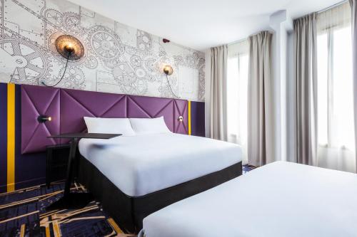 two beds in a room with a purple wall at ibis Styles Paris Mairie De Clichy in Clichy