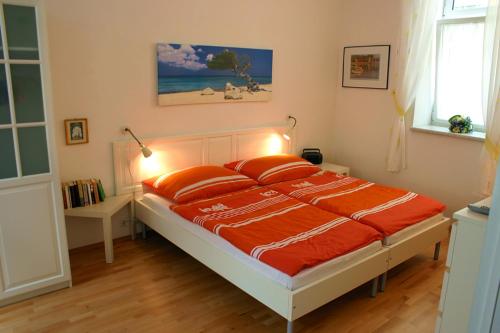 a bed with orange sheets and pillows in a bedroom at Apartment Haydnpark in Vienna