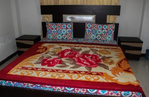 - un lit avec une couette colorée et des fleurs dans l'établissement Green Valley Bhurban Apartments, à Bhurban