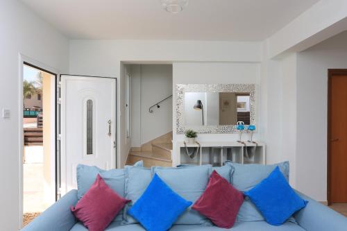 a living room with a blue couch with colorful pillows at SeaBreeze Villas by TrulyCyprus in Ayia Napa