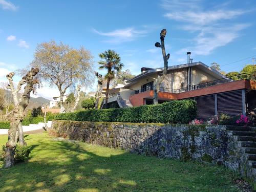 a house with a stone retaining wall and trees at Vivenda do Paúl in Geres
