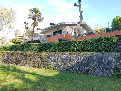 a house behind a stone retaining wall with a fence at Vivenda do Paúl in Geres