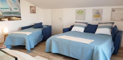 2 letti in una camera con lenzuola blu di ATTICO MARIS 104 a due passi dalla spiaggia Free Wi Fi ad Alghero