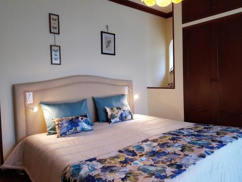 a bedroom with a large bed with blue pillows at Vivenda do Paúl in Geres