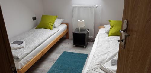 two beds in a small room with green pillows at Osada nad Potokiem in Szczyrk