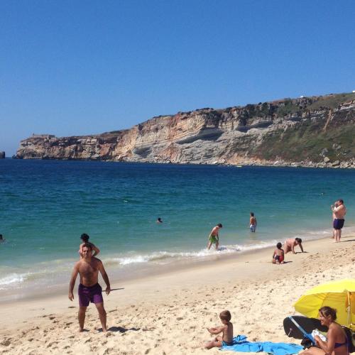 a group of people on a beach near the ocean at Appartement de standing in Nazaré