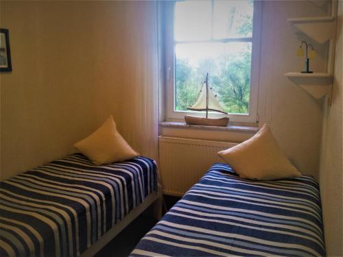 ein Zimmer mit 2 Betten und einem Fenster mit einem Segelboot auf der Fensterbank in der Unterkunft Eine schöne 3-Zimmer-Wohnung mit Ostsee-Zugang! in Juliusruh