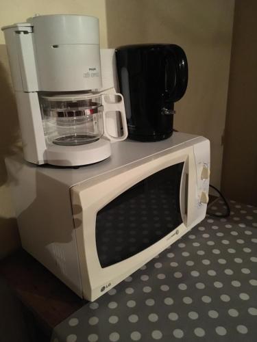 a microwave with a coffee maker on top of it at chambre privée in Lombron