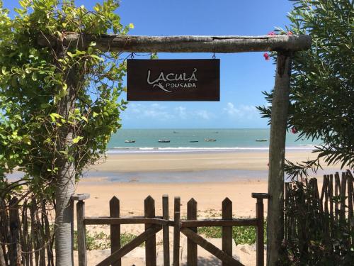 a sign for a beach with the ocean in the background at Pousada Lacula in Praia de Moitas