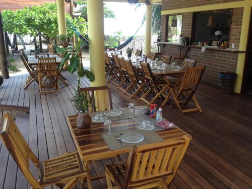 un restaurant avec des tables et des chaises sur une terrasse en bois dans l'établissement Pousada Lacula, à Praia de Moitas