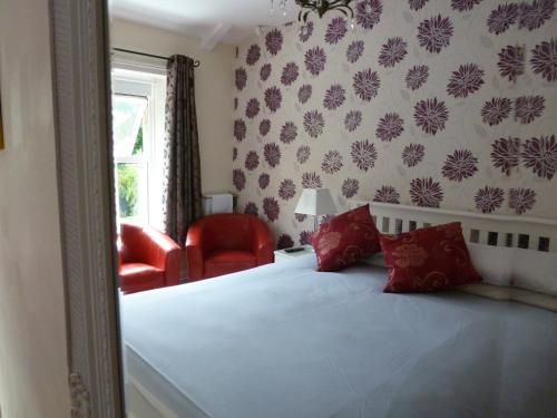 a bedroom with a bed and a red chair at Hedgefield House in Gateshead