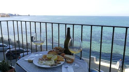 einen Tisch mit einem Teller Essen und zwei Gläsern Wein in der Unterkunft Appartamento Belvedere in Trapani