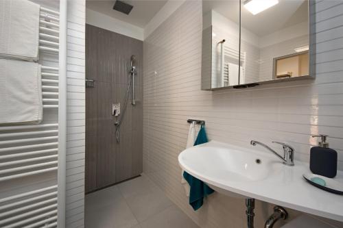 biała łazienka z umywalką i prysznicem w obiekcie apartmán Marica w mieście Luhačovice
