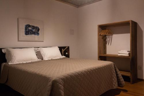 een slaapkamer met een bed met witte kussens en een spiegel bij Pousada Villa Madorna in Santana do Riacho