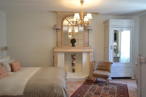a bedroom with a bed and a chair and a fireplace at La Maison Des Buis in Falaise