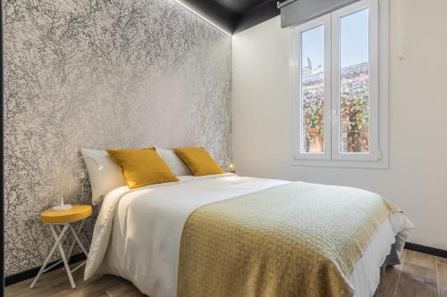 Un dormitorio con una cama con almohadas amarillas y una ventana. en Borgonuovo Apartments, en Bolonia