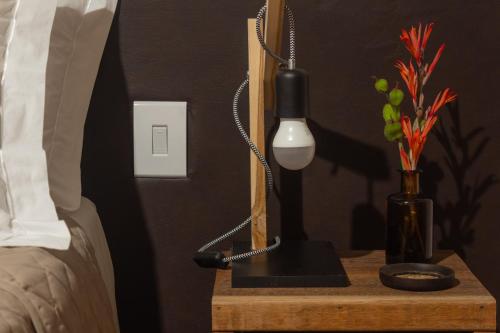 a night stand with a lamp and a vase with flowers at Villa Madorna in Santana do Riacho