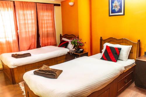 2 camas en una habitación con paredes de color naranja en Siddhi Home & Restaurant, en Bhaktapur