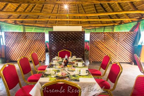 a table with red chairs in a room with a wall at Mirembe Resort Beach Hotel Ssese in Kalangala