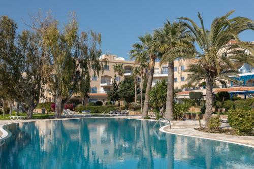 einem großen Pool mit Palmen vor einem Gebäude in der Unterkunft 105 Kings Palace - Fabulous 2 Bed, 2 bath, Large Patio with Garden - Sea Views in Paphos City