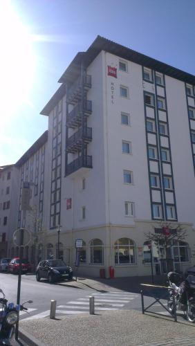 a large white building with cars parked in a parking lot at ibis Ciboure Saint-Jean-de-Luz in Ciboure