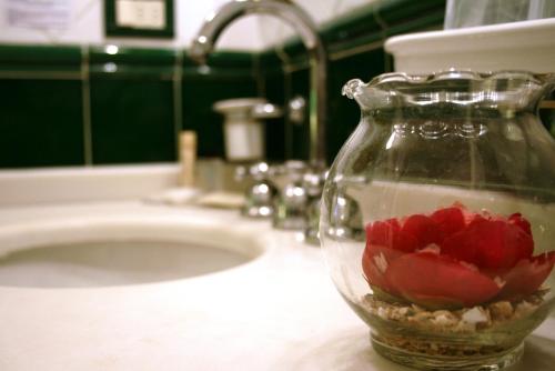 a glass vase with flowers in it on a bathroom sink at Hotel Rosary Garden in Florence