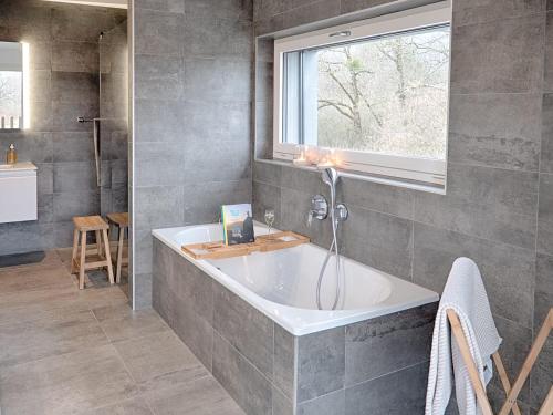 ein Bad mit einer Badewanne und einem Fenster in der Unterkunft Swiss Lake Lodge in Noville