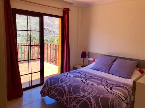 a bedroom with a bed and a door to a balcony at Apartamento Las Tejas Mogán in Mogán