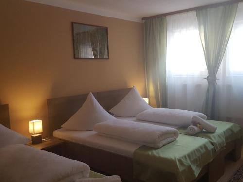 a bedroom with two beds with white pillows and a window at Complex Turistic Caprioara in Baia Mare