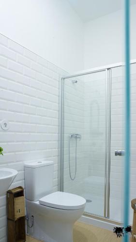 a bathroom with a toilet and a glass shower at República Guest House in Coimbra