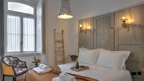 a bedroom with a white bed and a chair at República Guest House in Coimbra
