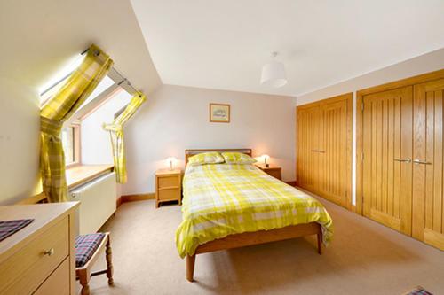 a bedroom with a yellow bed and a window at The Arches, Borthwick Mains Farm, in Gorebridge