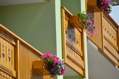 two balconies with flowers on the side of a building at Mason La Zondra in Vigo di Fassa