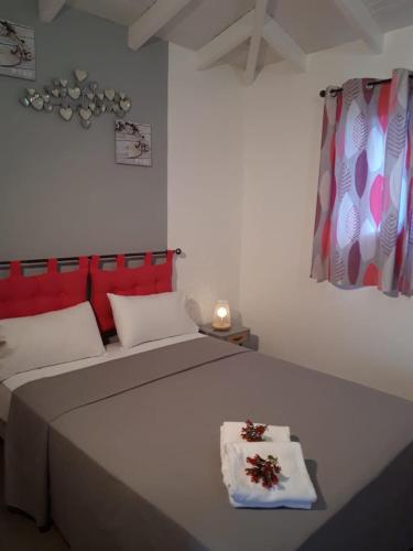 a bedroom with a bed with red and white pillows at LES MULTIPLIANTS in Le Moule