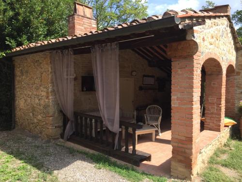 um pavilhão com uma mesa e uma cadeira num pátio em Agriturismo le Colline em Montescudaio