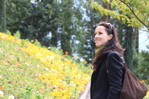a woman walking in front of a flower garden at Garni Brunnenhof in Caldaro