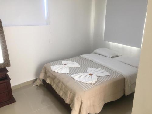 a bedroom with a bed with white towels on it at Villa Mary Hostal in Barranquilla