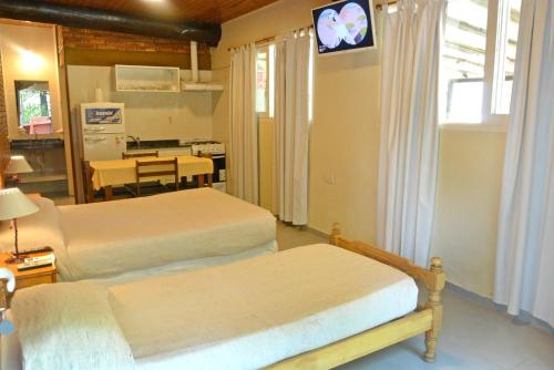 1 dormitorio con 2 camas y mesa con TV en Cabañas Las Marias en San Rafael