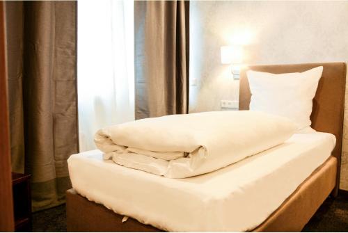 Bett mit weißer Bettwäsche und Kissen in einem Zimmer in der Unterkunft Langerfelder Hof in Wuppertal