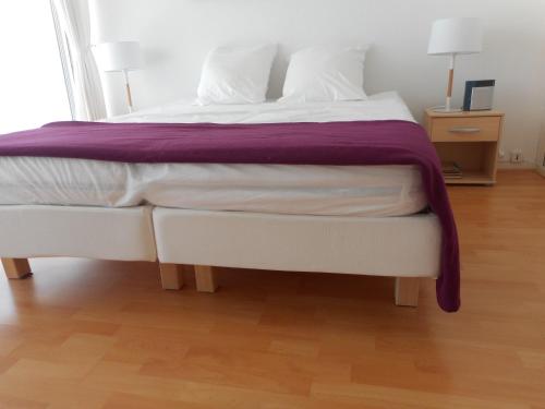 Una gran cama blanca con una manta morada. en T2 Bassin d'Arcachon, 100m plage, centre-ville en Andernos-les-Bains
