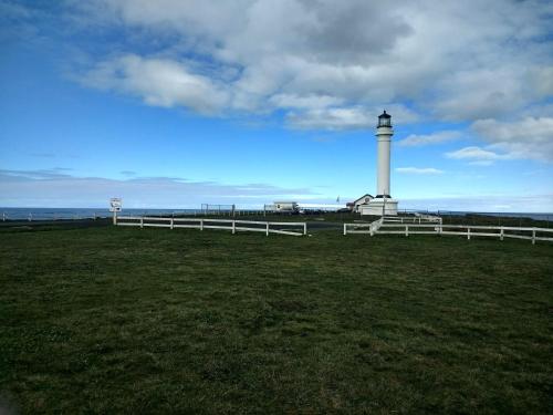 a lighthouse in a field with a white fence at Point Arena Lighthouse in Point Arena