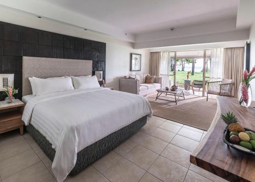 a bedroom with a large bed and a living room at Shangri-La Yanuca Island, Fiji in Voua