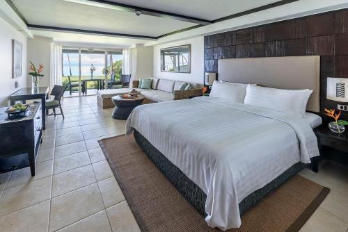 a bedroom with a large bed and a living room at Shangri-La Yanuca Island, Fiji in Voua