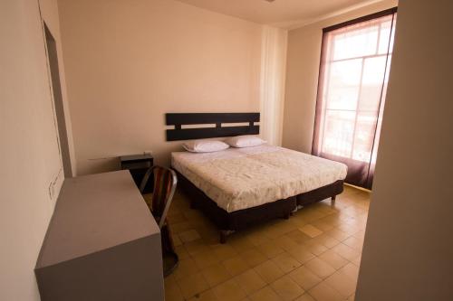 a bedroom with a bed and a table and a window at Casa de Juan Hostal in Xalapa