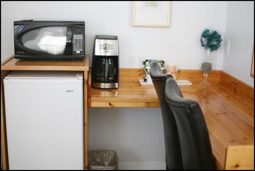 a wooden table with a microwave and a television on it at Quest Motel in Whitewood