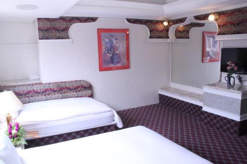 a small room with two beds and a tv at 貴都飯店-Crystal Hotel Taipei in Taipei