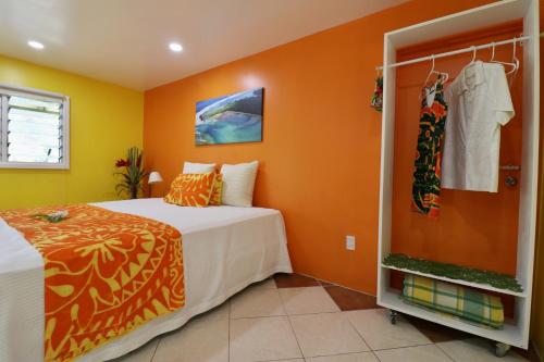 a bedroom with orange walls and a bed and a closet at ShineAwayHomes - Mountain View AIR CONDITIONED in Rarotonga